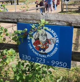 A blue flag with the Franklin the Plumber on a fence