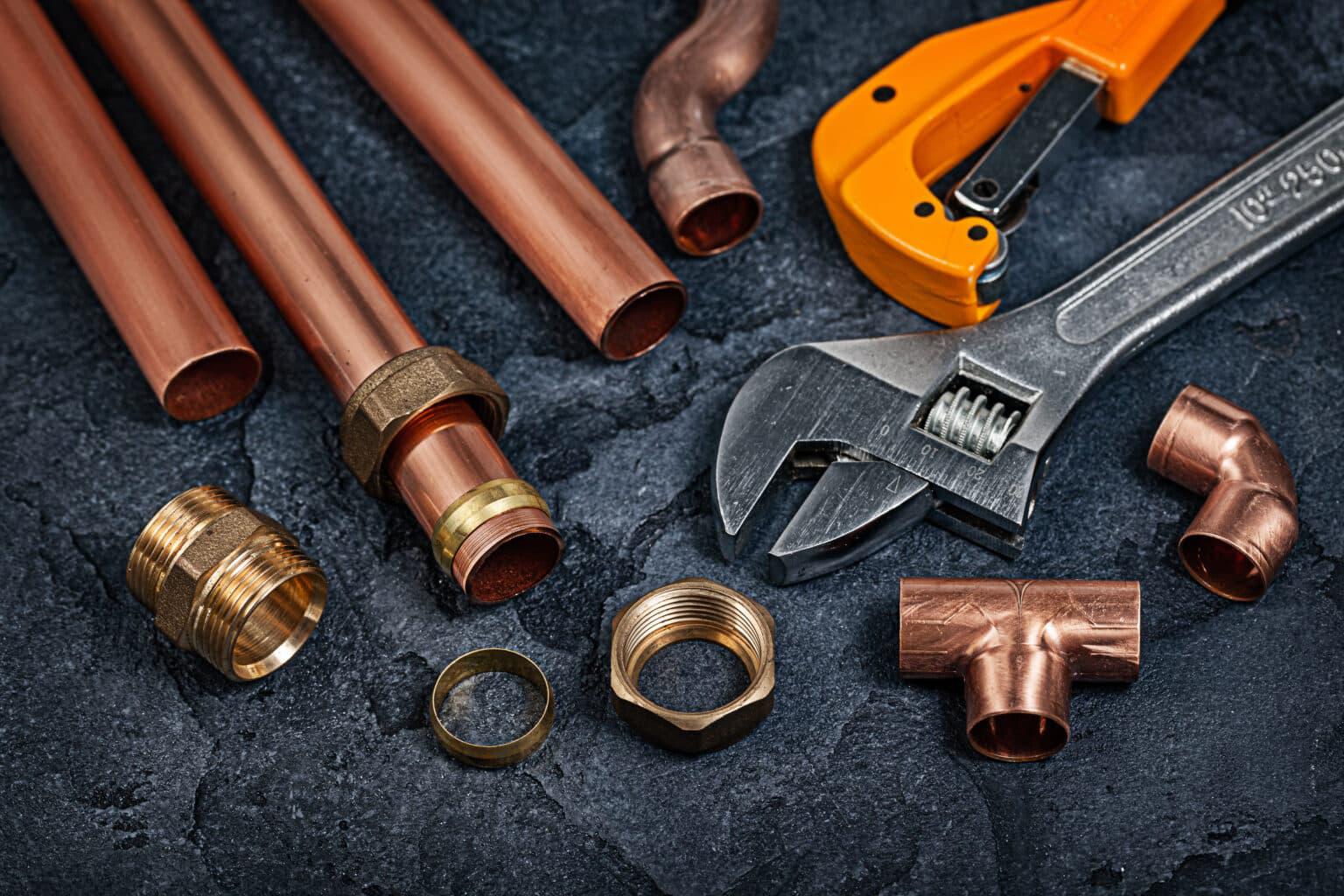 copper piping parts next to plumbing tools