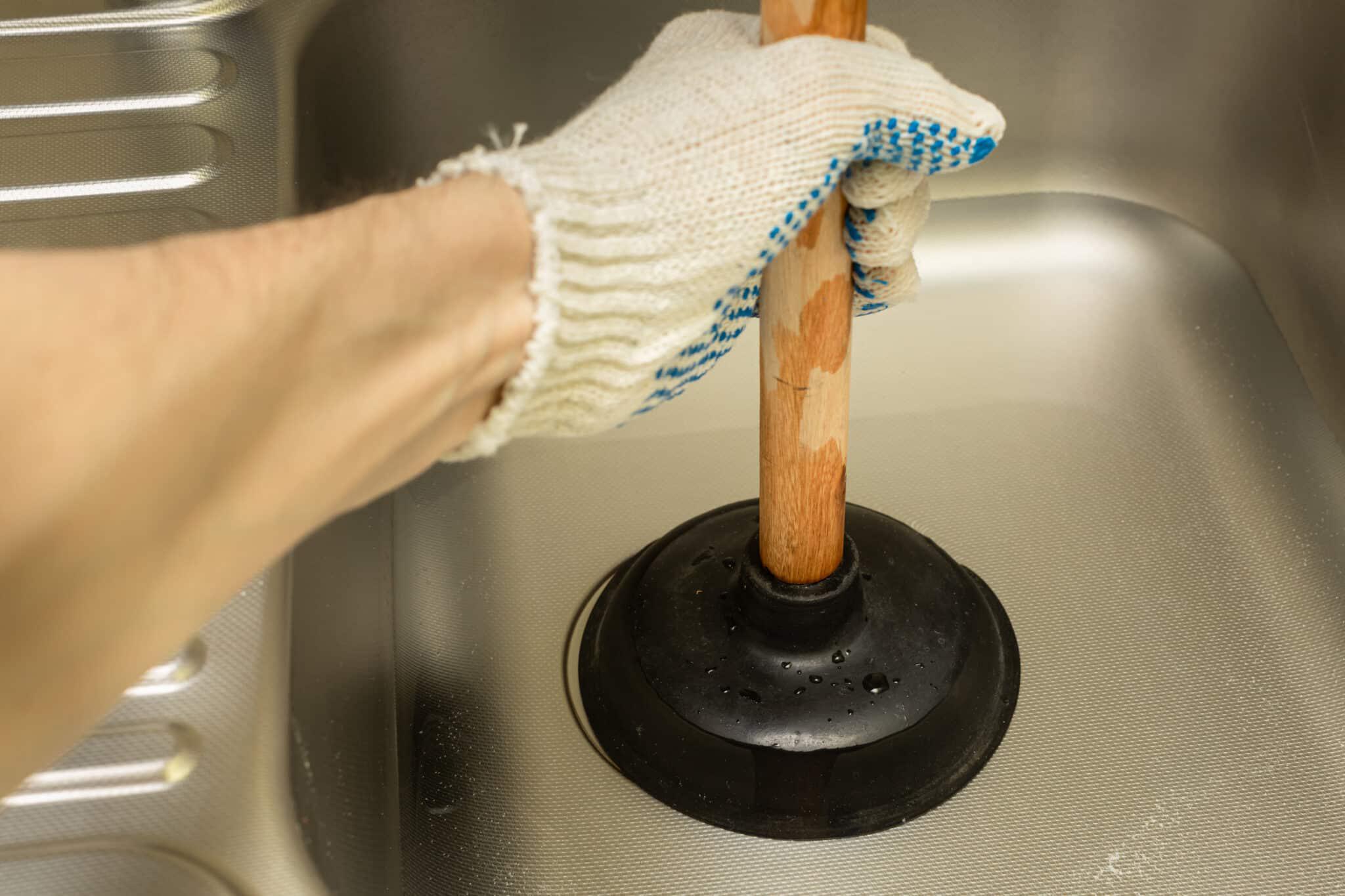 gloved hand plunging sink