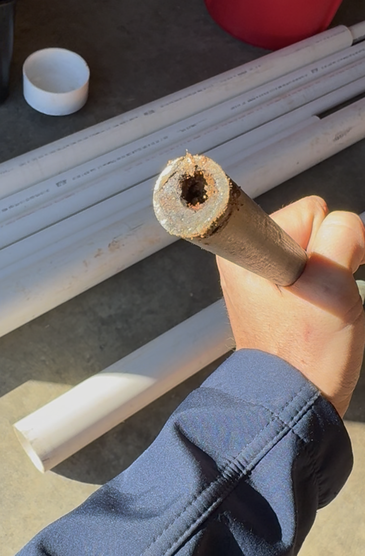 Cross-section of a corroded galvanized steel pipe showing heavy mineral scale and rust buildup