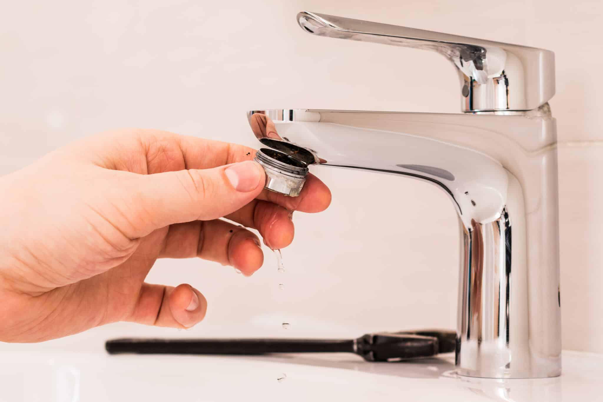 hand removing filter from faucet