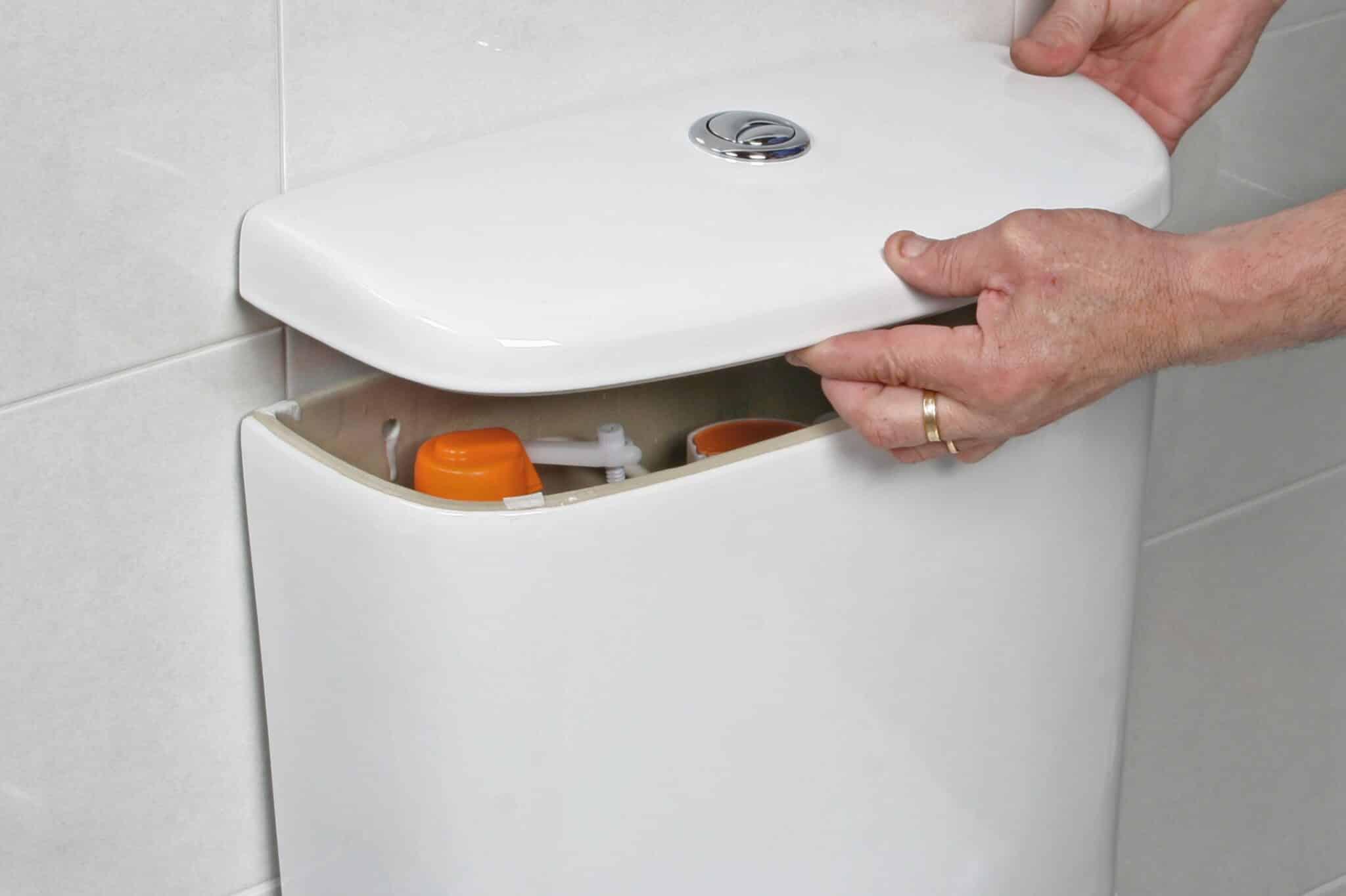 hands removing top of toilet to inspect flapper