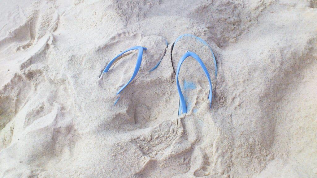 flip flops covered and surrounded by sand
