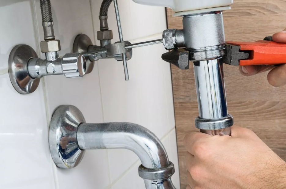 A plumber using a wrench on pipes
