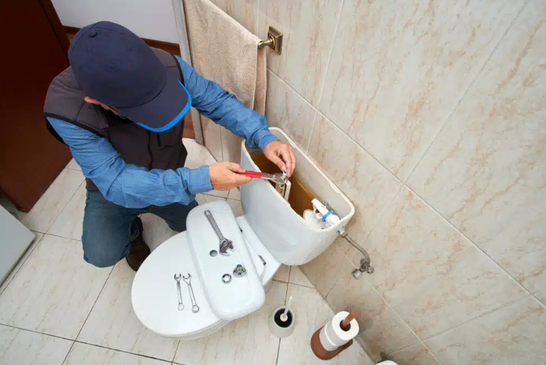 man fixing toilet with top open