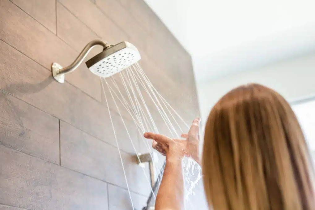 woman with hands up towards shower head