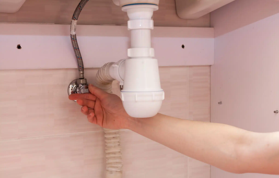 hand twisting water valve under sink