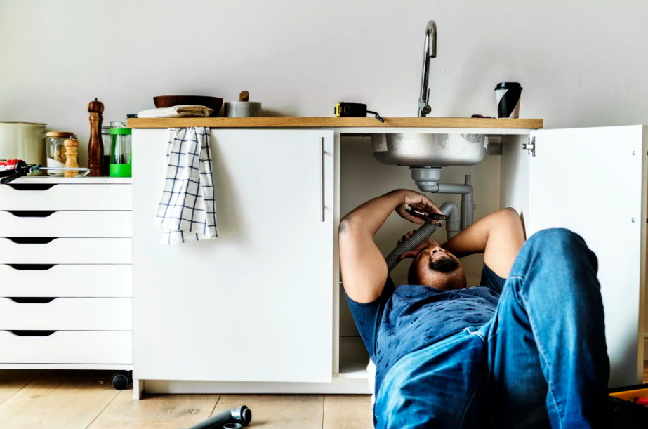 plumber working on piping under sink