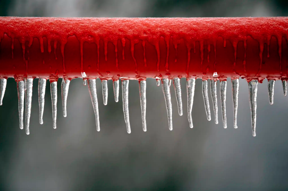 frozen red pipe with icicles hanging from it