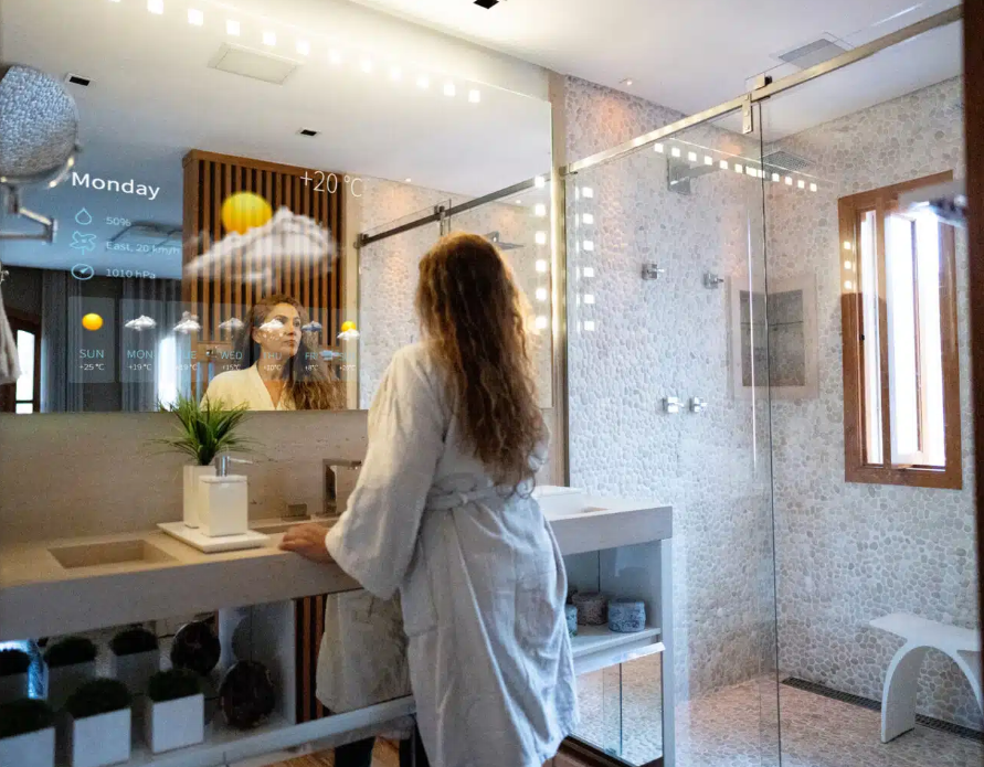 woman in robe looking in mirror with weather forecast on mirror