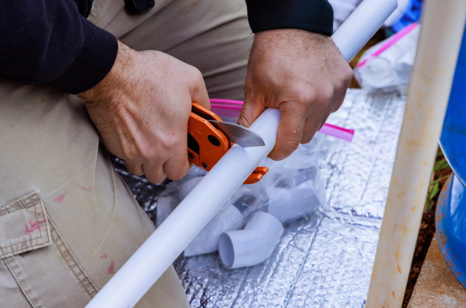 hands cutting plumbing pipe