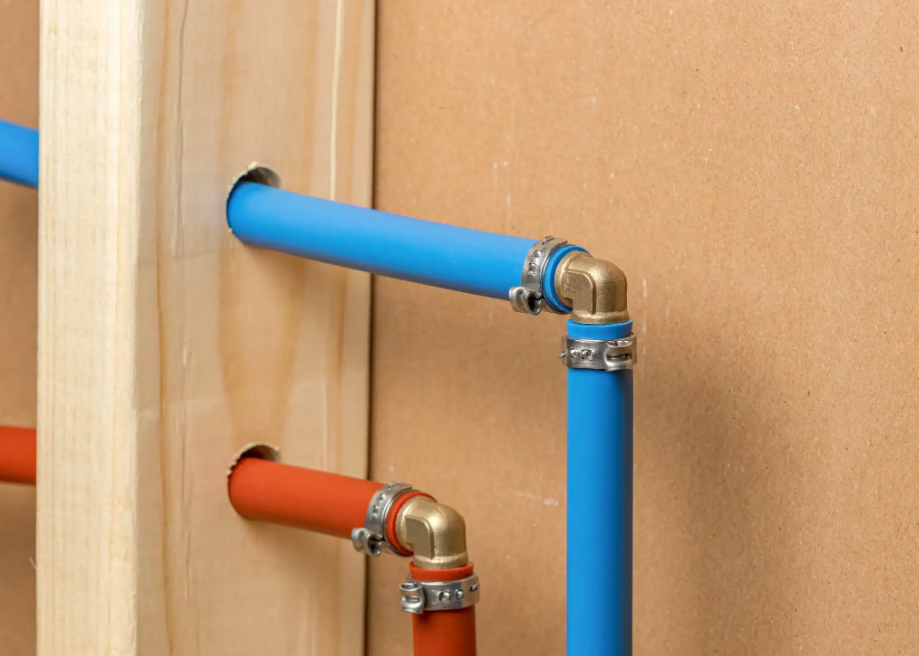 blue and red plumbing lines running through hole in wood