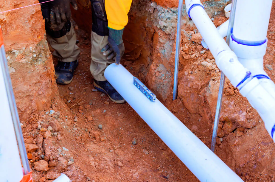 worker installing plumbing in ground