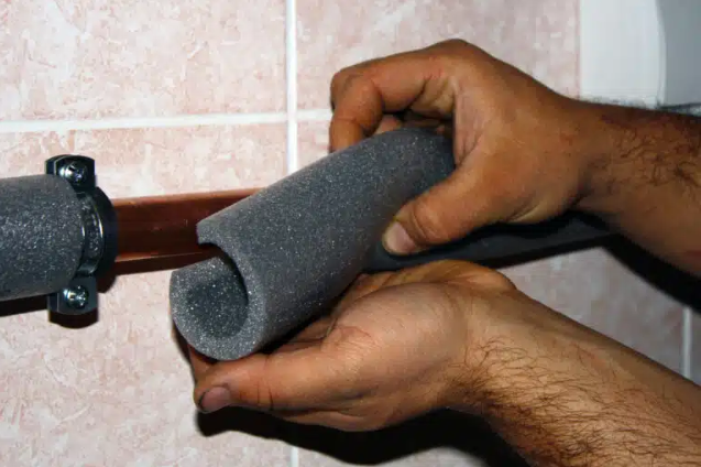 person putting foam around plumbing pipe