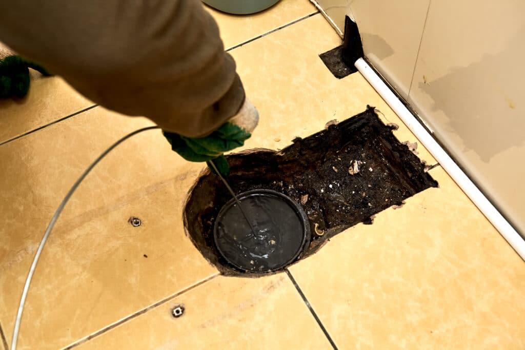 plumber cleaning drain from toilet